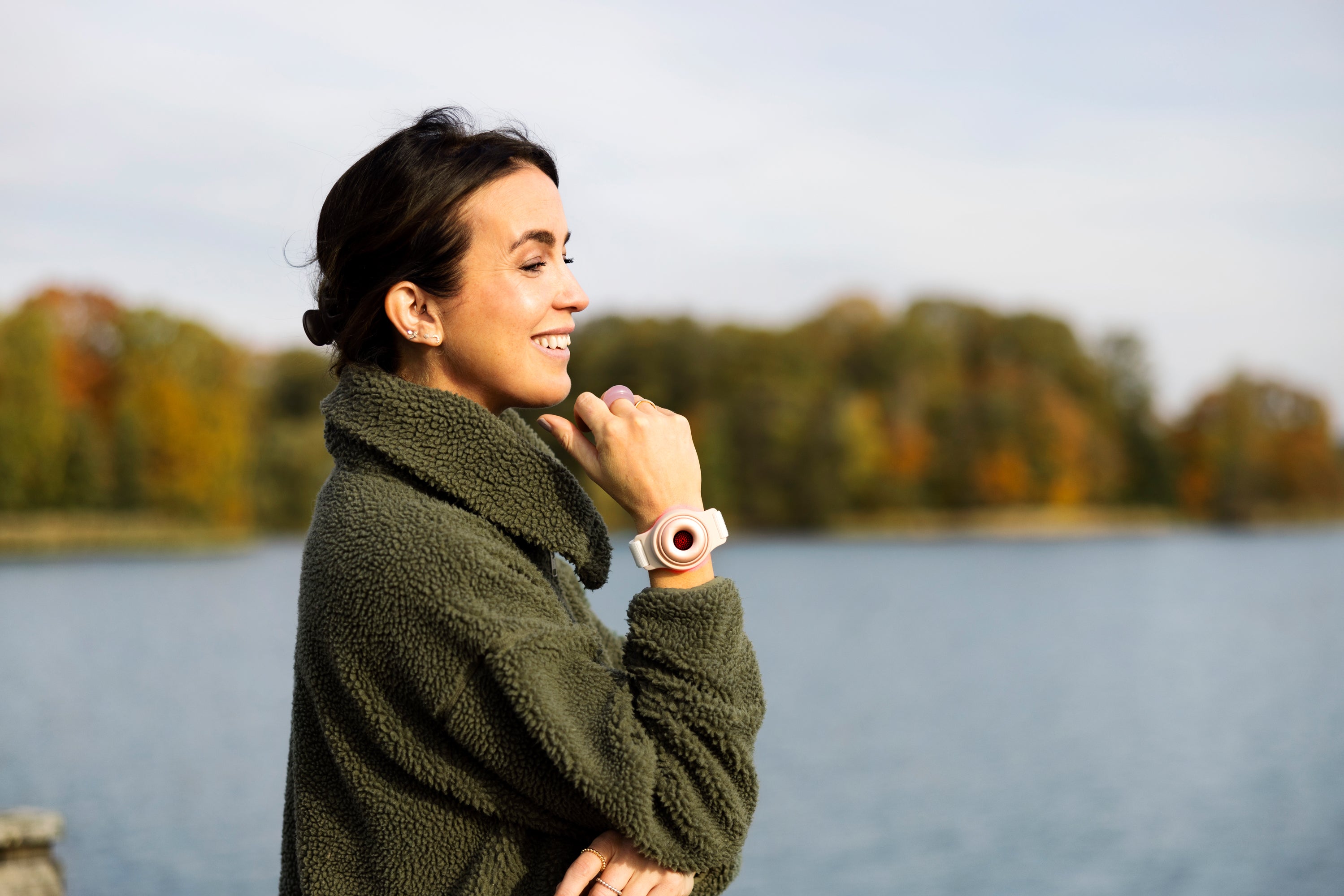 A woman by the water wearing a red light therapy bracelet