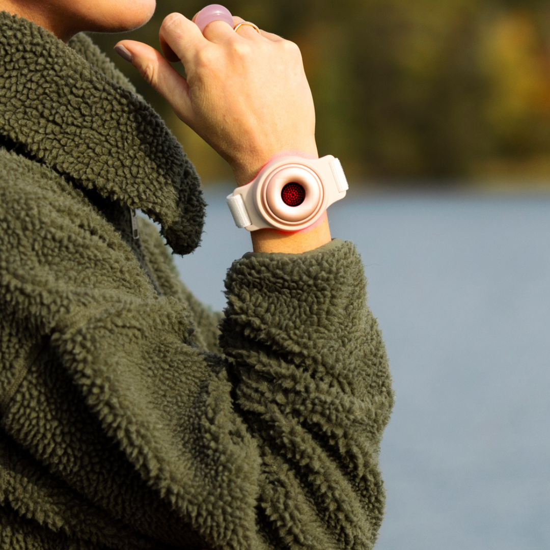 A woman by the water wearing a red light therapy bracelet